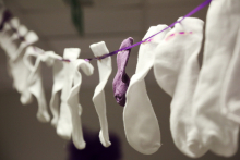 White socks hanging on a string. Among them is one purple sock.