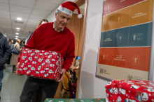 A man carrying a gift wrapped in red paper.