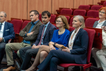 Symposium participants seated in red chairs.