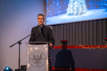 Canon priest Mateusz Gawarski is standing at a lectern and speaking into a microphone.