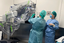 Lekarze ubrani w niebieskie fartuchy obok dużego mikroskopu do przeprowadzenia rekonstrukcji.