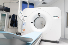 A modern CT scanner in a bright, sterile medical room.