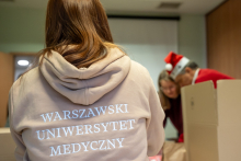 Na pierwszym planie dziewczyna w jasnej bluzie z napisem Warszawski Uniwersytet Medyczny, w tle inne osoby.