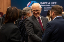 Several people are standing and talking in a conference room during the event “SAVE A LIFE – World Congress of Polish Medical Communities.” In the foreground is the rector of the Medical University of Warsaw.