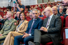 A group of conference participants. They are sitting and talking, some are looking ahead. 