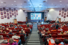 A shot of the auditorium, where many people are sitting. 