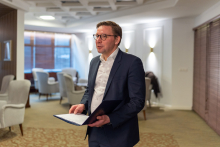 Elegancko ubrany mężczyzna z otwartą teczką trzymaną w dłoniach przemawia na spotkania.