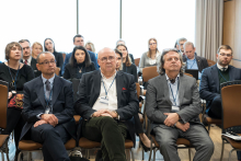 Kilkanaście w kilku rzędach w sali konferencyjnej. Wszyscy patrzą w kierunku prelegenta, którego nie widać w kadrze