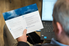 Mężczyzna trzymający otwartą ulotkę z programem konferencji.