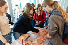 Participants are taking part in breast self‑examination workshops, using anatomical models arranged on the table. Under the guidance of the instructors, they practice palpation techniques for detecting abnormalities.
