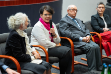 A discussion panel during the ceremony; one of the participants is holding a microphone and speaking, while the other panelists are seated beside her in armchairs.