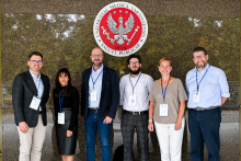 A group of six people standing under the emblem of the Medical University of Warsaw, posing for a group photo during an event