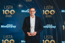 A person in formal attire holding an award trophy while standing in front of a ‘Lista 100 2025’ and ‘Puls Medycyny’ event backdrop.