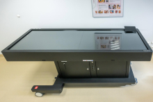 A modern medical simulator by Surgical Science with a large monitor and a control panel, placed in a bright training room.