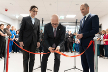 Ribbon‑cutting ceremony taking place in a hospital corridor, with three formally dressed individuals standing at the front and a group of staff members gathered in the background.