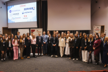 Grupowe zdjęcie uczestników i prelegentów stojących na scenie podczas wydarzenia edukacyjnego w sali konferencyjnej, z widocznymi roll-upami oraz ekranem prezentującym logotypy sponsorów