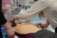 Osoby ćwiczą procedurę medyczną na fantomie, wykonując defibrylację i wentylację w ramach szkolenia z resuscytacji.