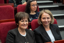 Trzy osoby siedzące w czerwonych fotelach audytorium. 