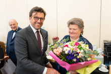 During the ceremony, a man in a suit presents a woman with a large bouquet of colorful flowers.