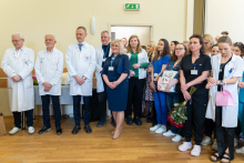 A group of medical professionals are standing together during a ceremony, with some of them holding flowers and gifts.