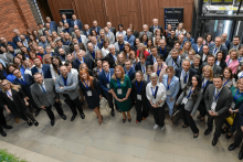 Grupa kilkudziesięciu osób pozuje do zdjęcia zbiorowego. Większość osób uśmiecha się.