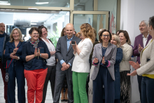  Grupa osób zgromadzonych w holu budynku klaszcze. Jedna z osób na środku trzyma w rękach telefon, a pozostałe osoby skierowane są w tę samą stronę.