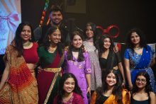 A group of performers posing together on stage, wearing colorful traditional garments after a performance.
