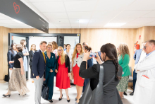 A group of people poses for a photo in a corridor, while one person holds a phone and takes the picture.