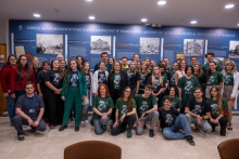 A group photo of participants and organizers of an educational event in a museum space. Dozens of people stand and kneel in front of exhibition boards dedicated to the history of academic medical education in Warsaw.