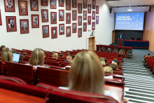 Widok ogólny auli z liczną publicznością. Na scenie widoczna mównica i ekran z prezentacją konferencji „Uczelniany Dzień Zdrowia Publicznego”.