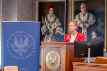 One person stands at a lectern and speaks during a conference. A screen and a Medical University of Warsaw banner are visible nearby.