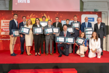 A group of women and men pose together on stage, each holding framed certificates received during the Perspektywy ranking awards ceremony.