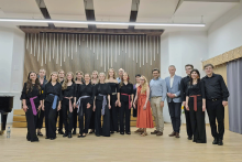 Grupa kilkunastu osób stoi na scenie i pozuje do zdjęcia.