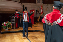 A male graduate walks across the stage with his arms outstretched after receiving recognition during the ceremony.