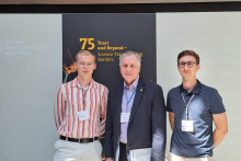 Trzech mężczyzn pozuje do zdjęcia przed ścianką konferencji Lindau Nobel Laureate Meetings.
