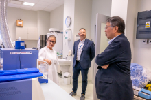 Trzy osoby odwiedzają laboratorium. Jedna osoba prezentuje wyposażenie pracowni, a pozostałe słuchają objaśnień.