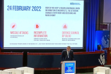 A presentation on regional governance during wartime and crisis is displayed on a large conference screen.