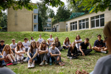 Group portrait of participants and organizers seated on steps outside a building.