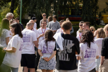 Participants wearing event T-shirts gathered outdoors in a circle during an orientation or group activity.