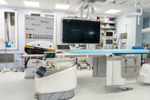 Procedure room equipped with a modern angiography system, medical monitor and patient monitoring stations. Signage of Brodnowski Hospital is visible.