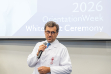 Mężczyzna w białym fartuchu przemawia podczas ceremonii.
