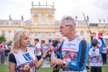 A participant gives an interview to a television reporter during the “Run for New Life” event. Other participants and the Museum of King Jan III’s Palace at Wilanów are visible in the background.