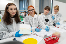 Grupa uczestników siedzi przy stole laboratoryjnym, analizując wyniki ćwiczeń i przygotowując próbki do badań.