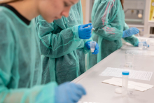 Uczestnicy w odzieży ochronnej przygotowują i analizują próbki podczas zajęć laboratoryjnych.