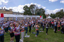 A large group of participants gathers on the lawn before the start of the walk. Event tents and the buildings of the Museum of King Jan III’s Palace at Wilanów are visible in the background.