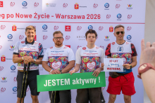 Four participants pose for a photo in front of the “31st Run for New Life – Warsaw 2026” event backdrop. Two participants hold a green sign reading “I am active!”, while another participant holds a sign marking 10 years since a liver transplant.