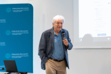 Osoba wygłasza prezentację przed uczestnikami Forum WUM-PW. Na ekranie wyświetlony jest slajd dotyczący badań naukowych.