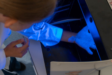 Uczestnik umieszcza próbkę w urządzeniu wyposażonym w podświetlaną komorę do analizy laboratoryjnej.