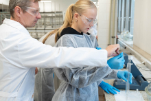 Prowadzący instruuje uczestniczkę podczas wykonywania pomiaru laboratoryjnego przy stanowisku z aparaturą.