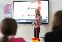 Prowadząca prezentuje zagadnienia związane z grupami krwi na ekranie multimedialnym podczas zajęć edukacyjnych.